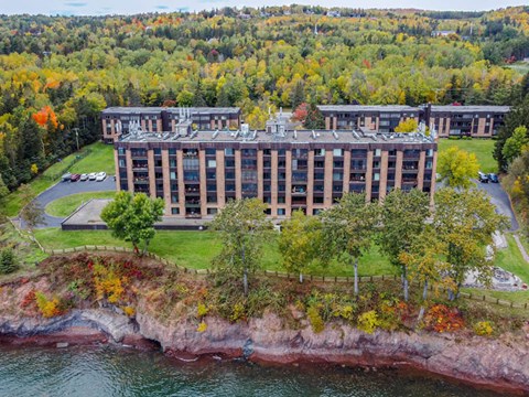 A large building sits on a cliff overlooking a body of water.