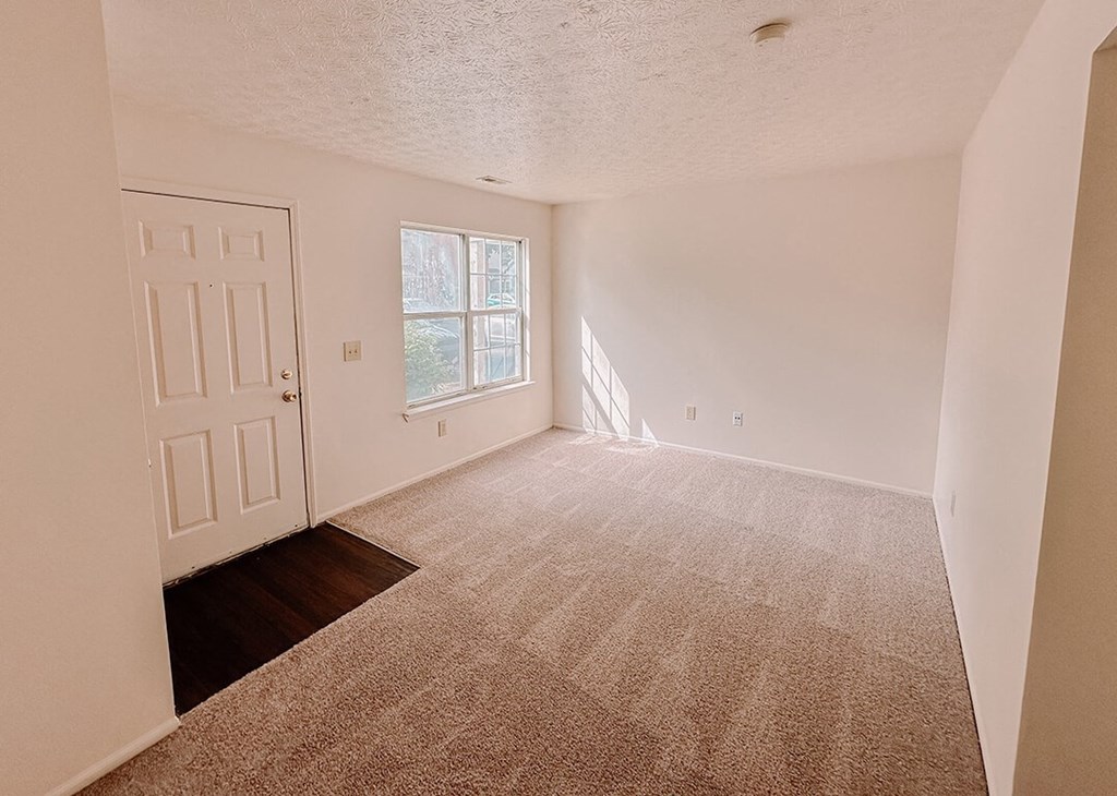 an empty living room with a white door and carpet