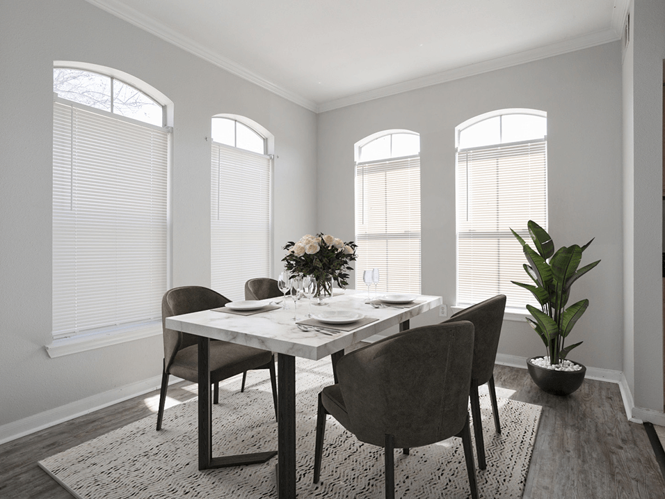 a dining room with windows and a table with a vase of flowers on top of it