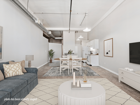 A living room with a grey couch, a white coffee table, and a white dining table.