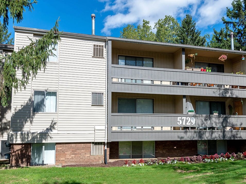 a white apartment building with a yard and grass