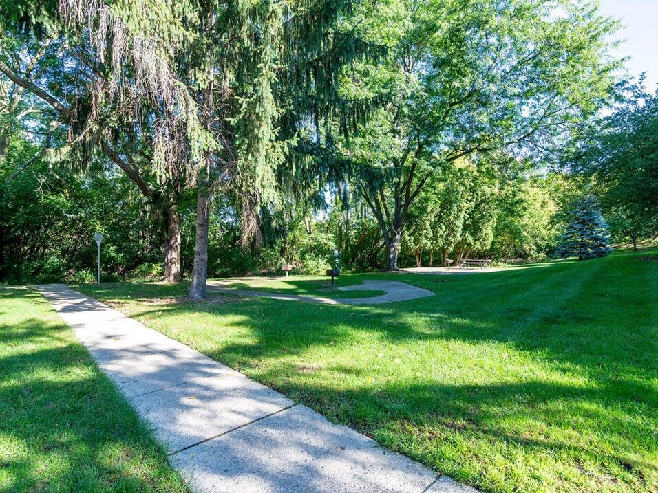 a park with trees and grass and a sidewalk