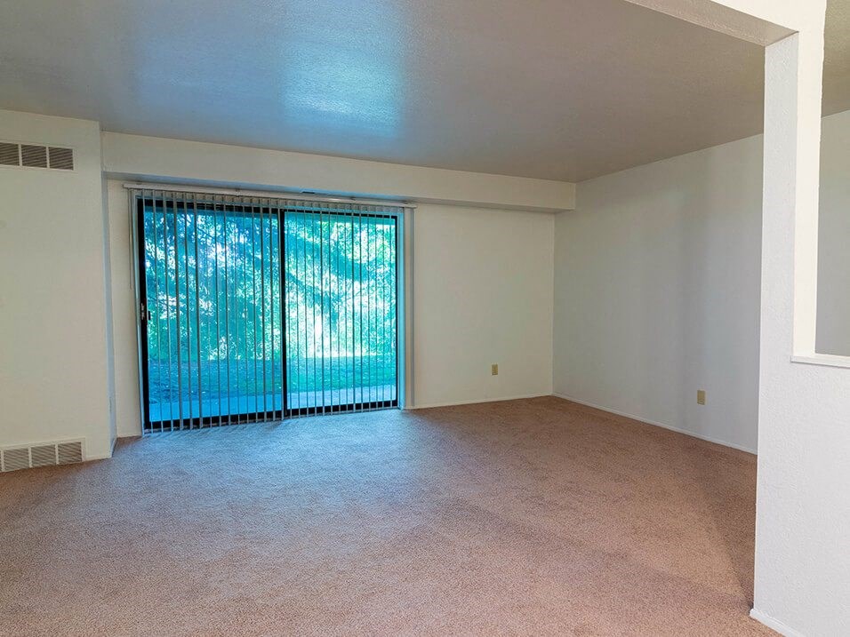an empty living room with a large window and carpet