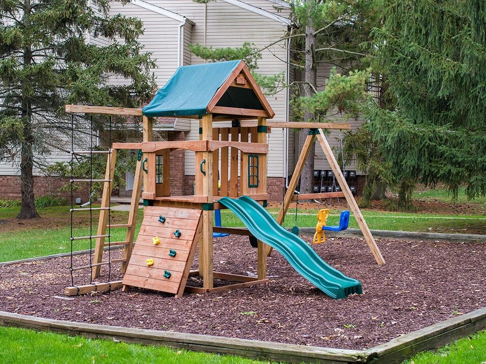 a wooden swing set with a slide in a backyard