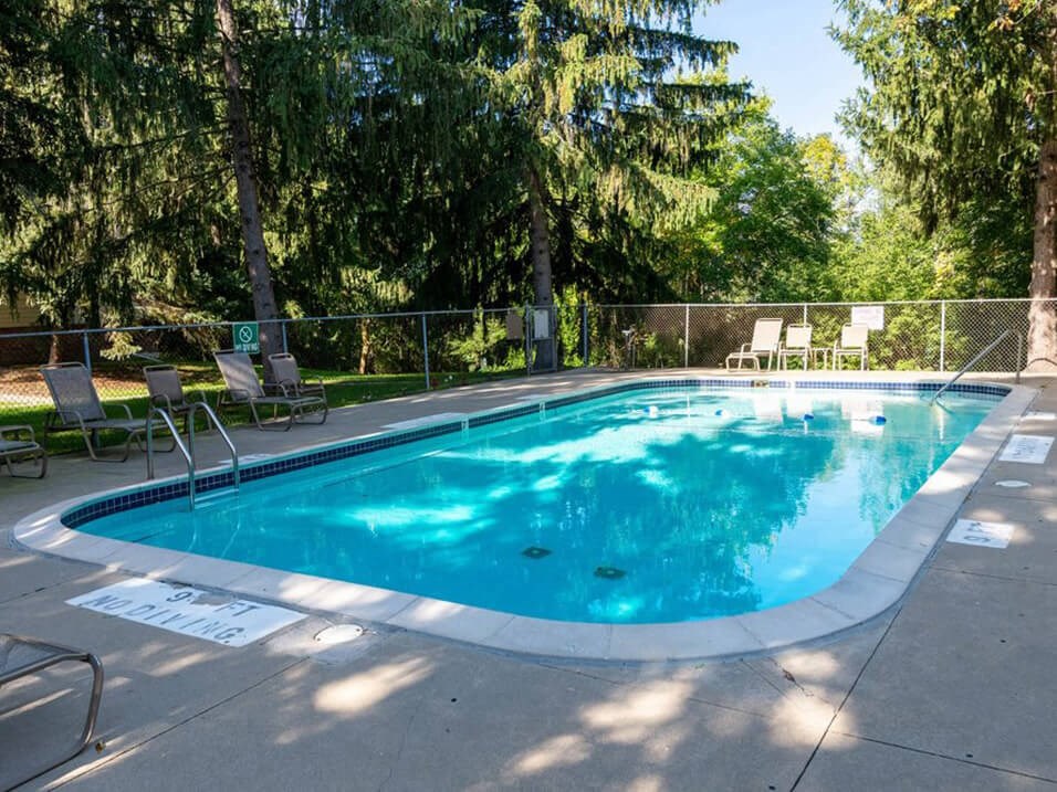 a swimming pool with chairs and a fence around it