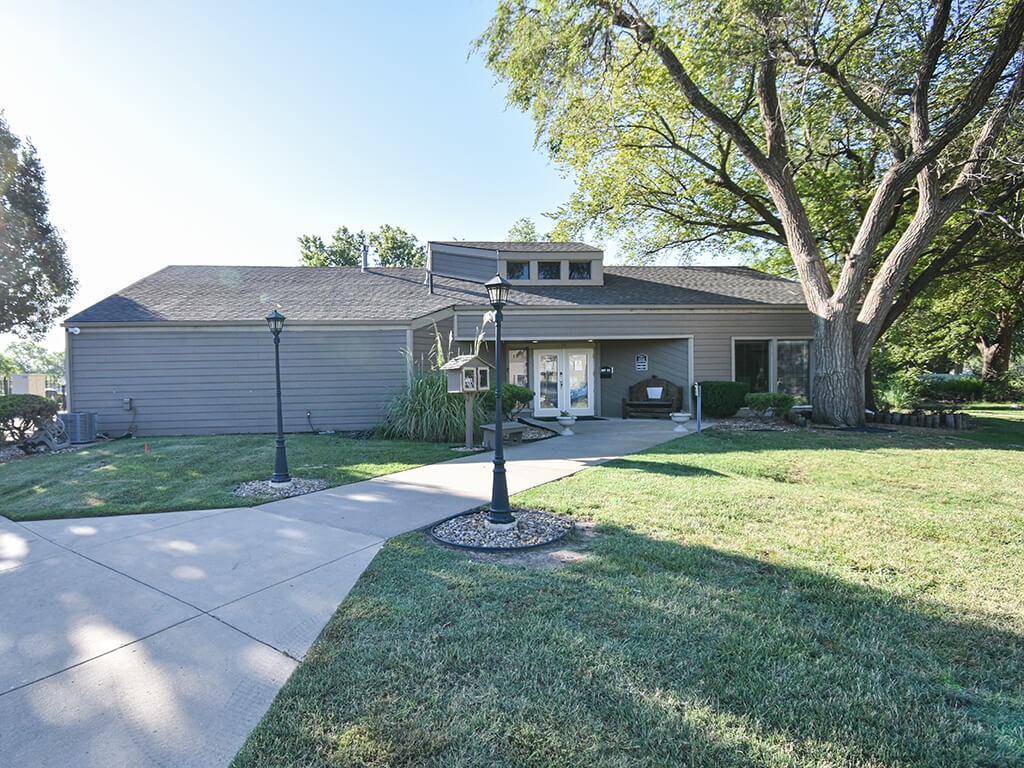 A house with a grey roof and a tree in front of it.