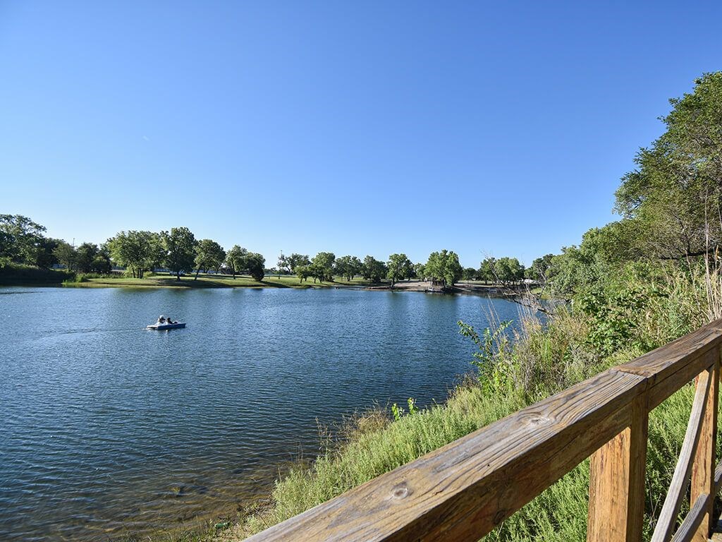 A serene lake with a boat and a forested shore.