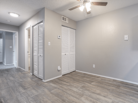 an empty living room with a ceiling fan and a closet