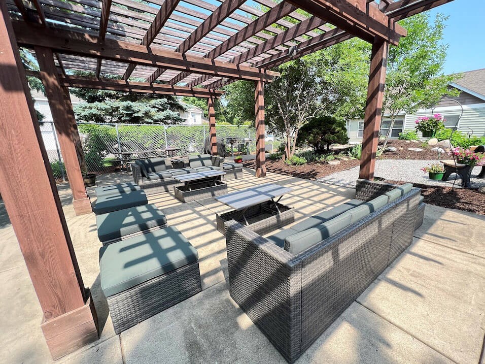 a covered patio with wicker furniture and a wooden pergola
