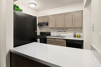 a kitchen with a white counter top and a black refrigerator
