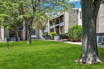 an apartment building with green grass and trees in front of it