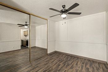 an empty living room with a ceiling fan and a mirror