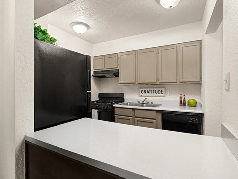 a kitchen with a white counter top and a black refrigerator
