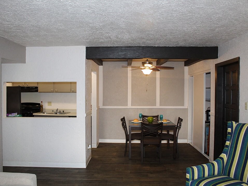 a dining room with a table and chairs and a kitchen in the background