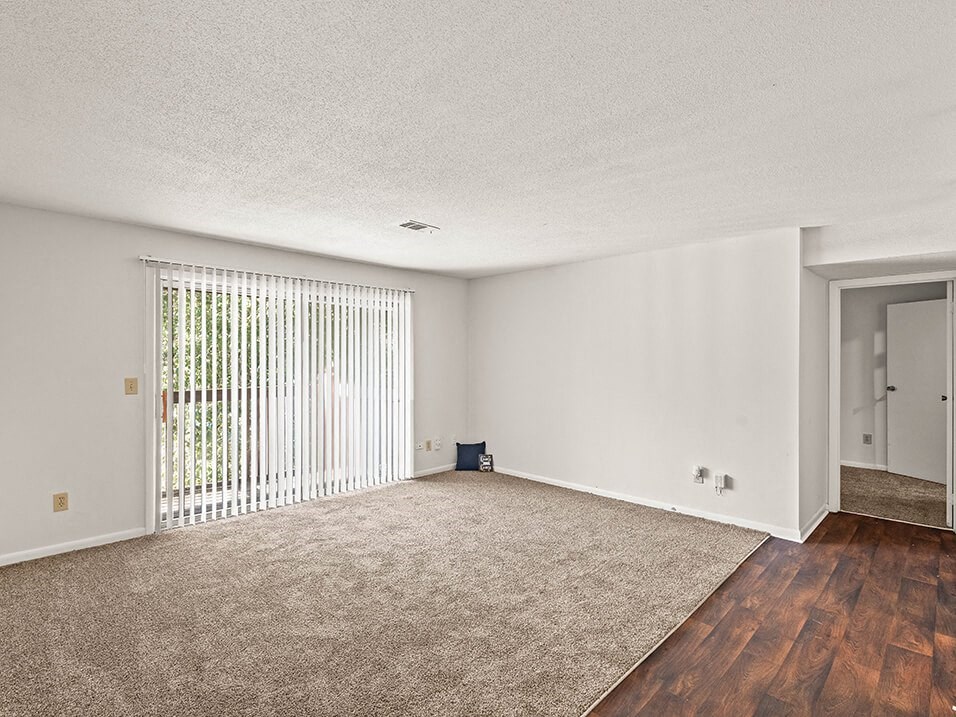 an empty living room with white walls and a sliding glass door