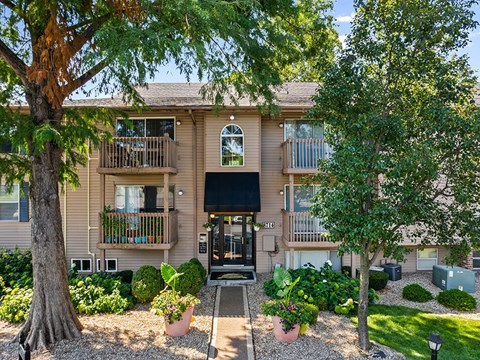front view of an apartment building with trees and a pathway