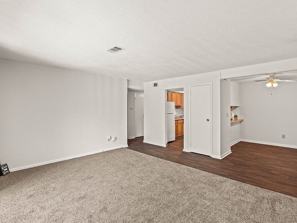 an empty living room with wood flooring and white walls