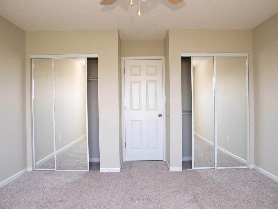 an empty bedroom with mirrored closets and a white door