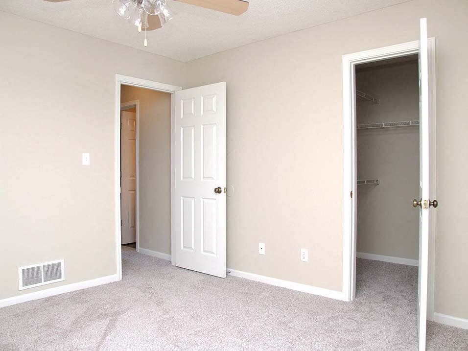 an empty bedroom with a closet and a white door