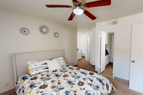 A bedroom with a bed and a ceiling fan.