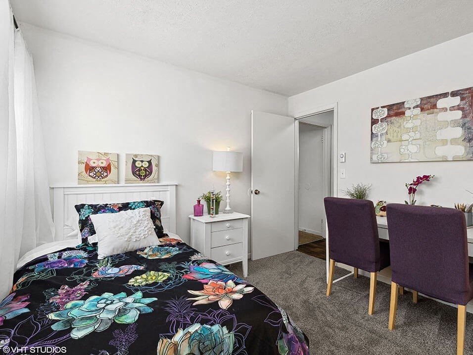 a bedroom with a bed and a desk with two chairs