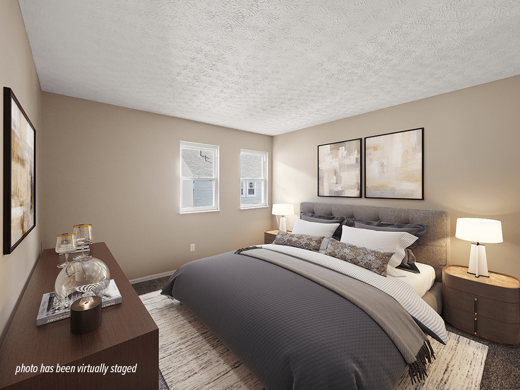 A bedroom with a large bed and a nightstand with a lamp.