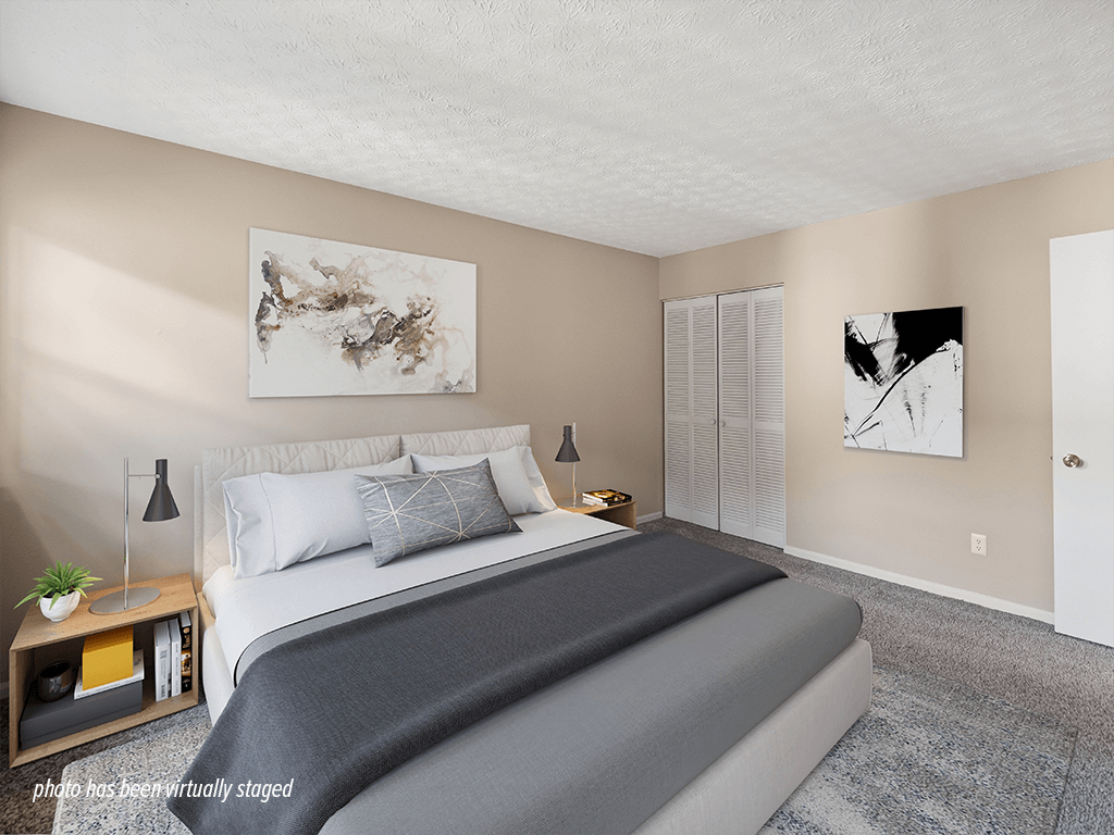 A bedroom with a large bed and two artworks on the wall.