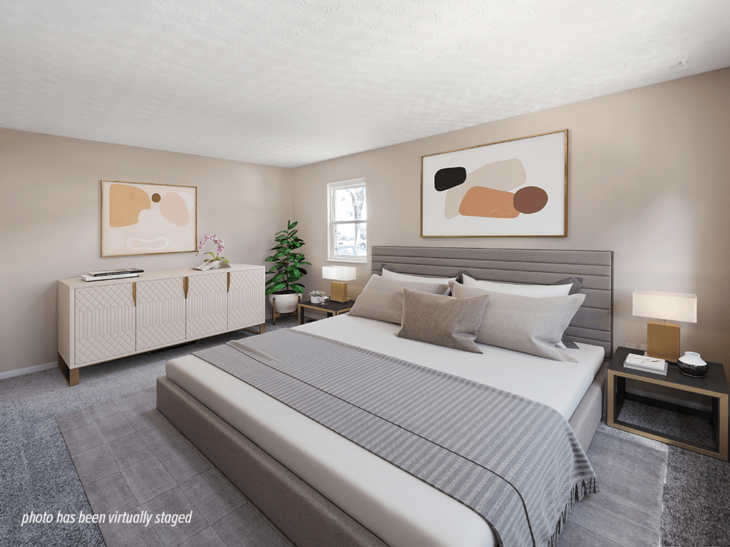 A bedroom with a large bed and a nightstand with a lamp.