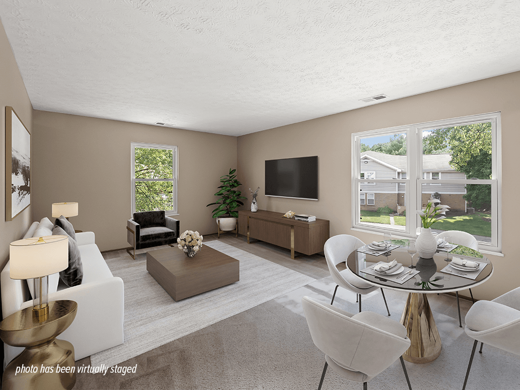 A living room with a white couch, a coffee table, a TV, and a dining table.
