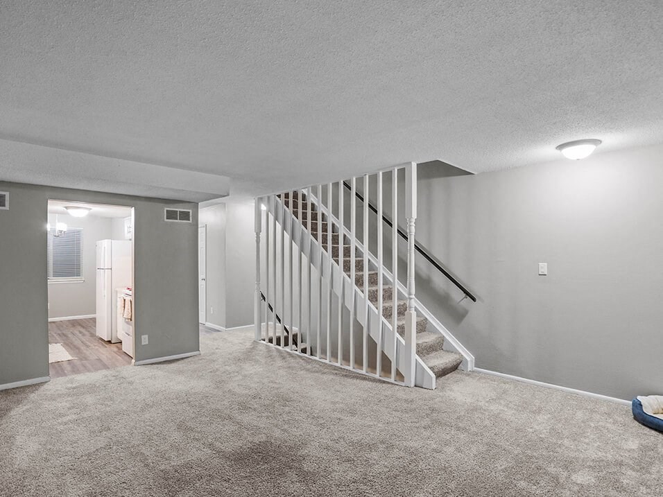 a white carpeted living room with a staircase