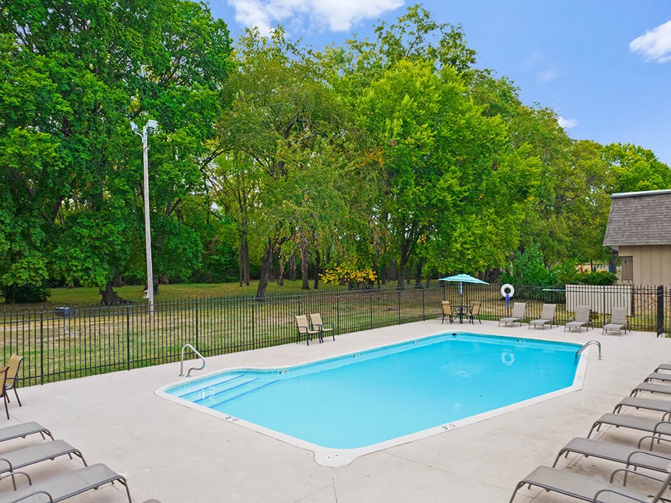 a swimming pool with chairs and a fence around it