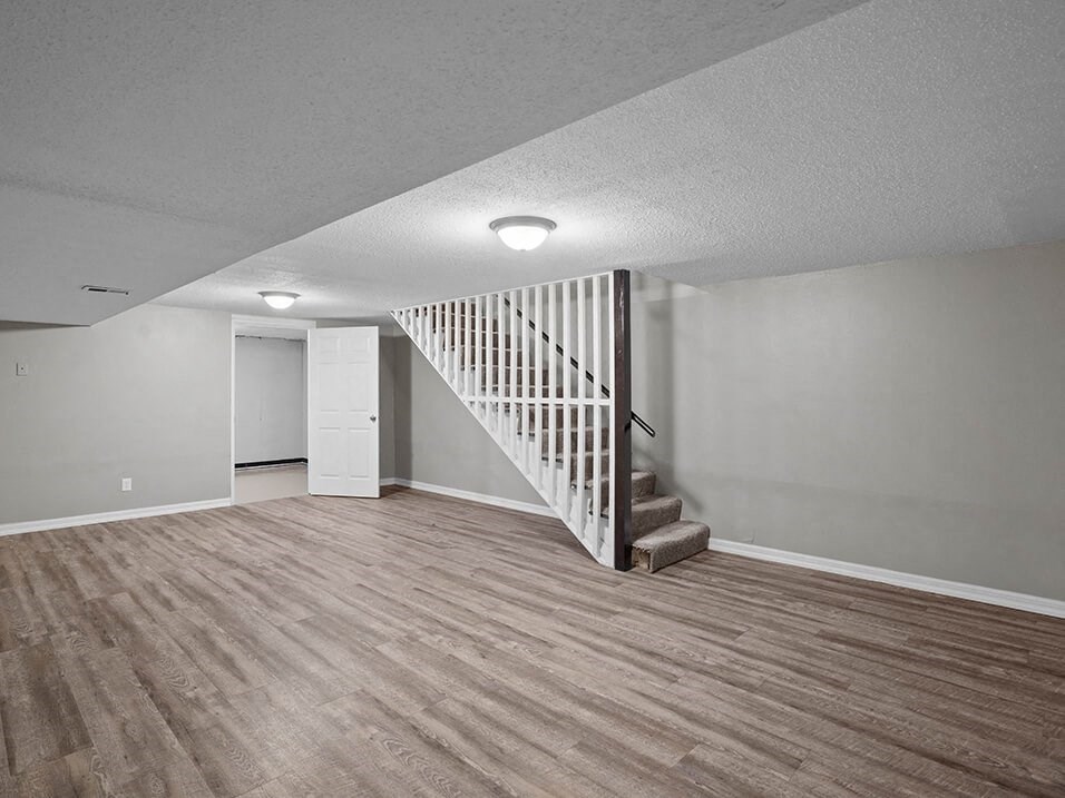 an empty living room with a white staircase and wood flooring