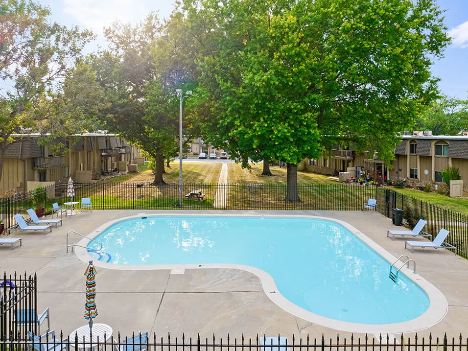 a swimming pool with chairs around it next to trees