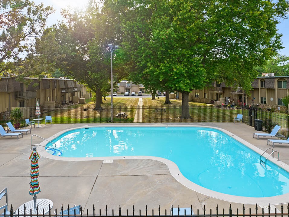 a swimming pool with chairs around it and trees