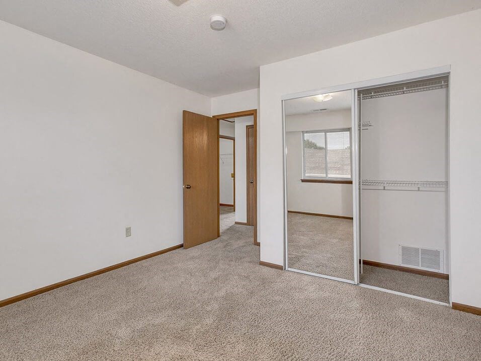 Carpeted bedroom with closet with mirror