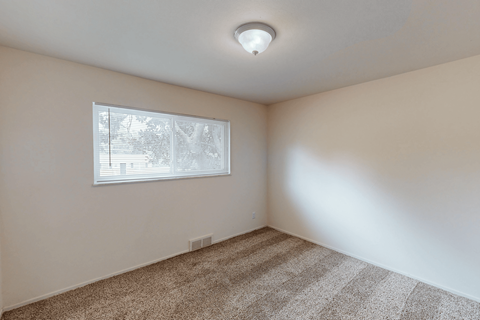 A room with a carpeted floor and a window.