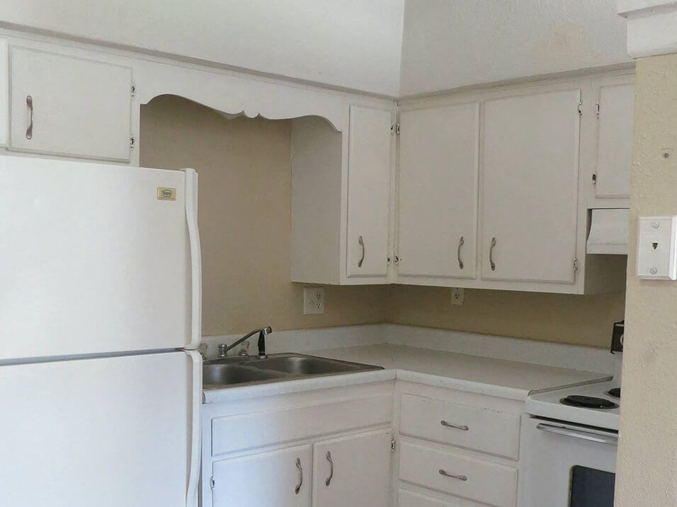 a kitchen with white cabinets and a refrigerator and a sink