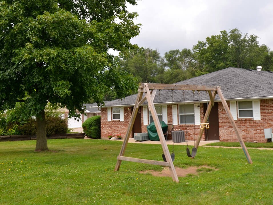 a swing set in a yard in front of a house
