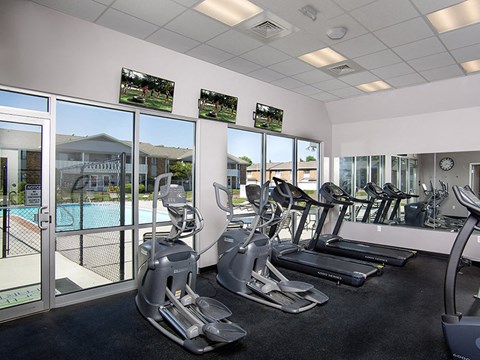 a gym with cardio equipment and windows overlooking a pool