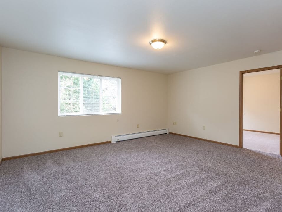 a bedroom with white walls and a large window