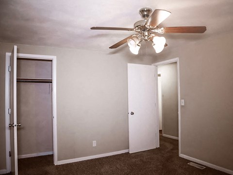 a bedroom with a ceiling fan and a closet