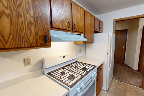A kitchen with a white stove top oven and wooden cabinets.