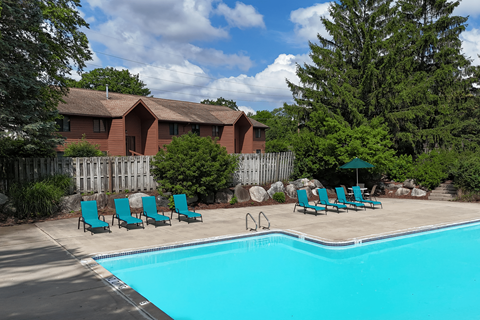A pool with chairs and a house in the background.