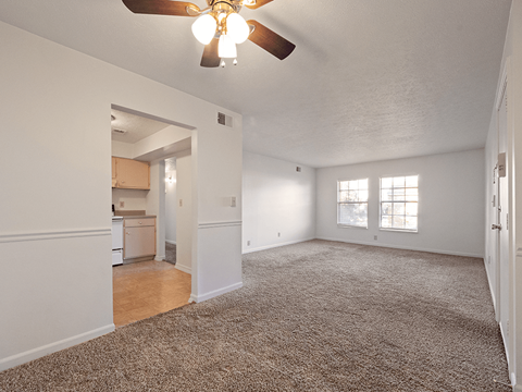 A room with a ceiling fan and carpeted floor.
