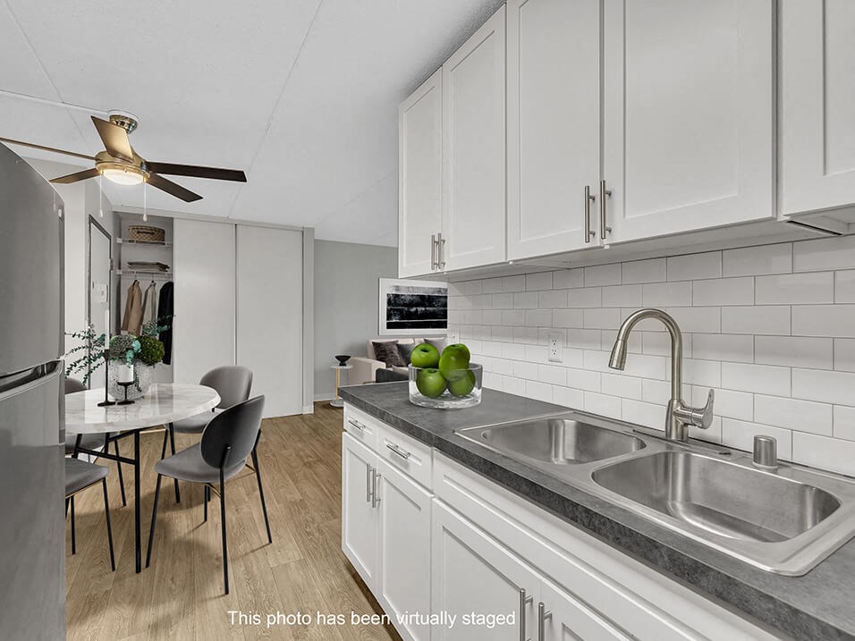 a kitchen with white cabinets and a sink and a table with chairs