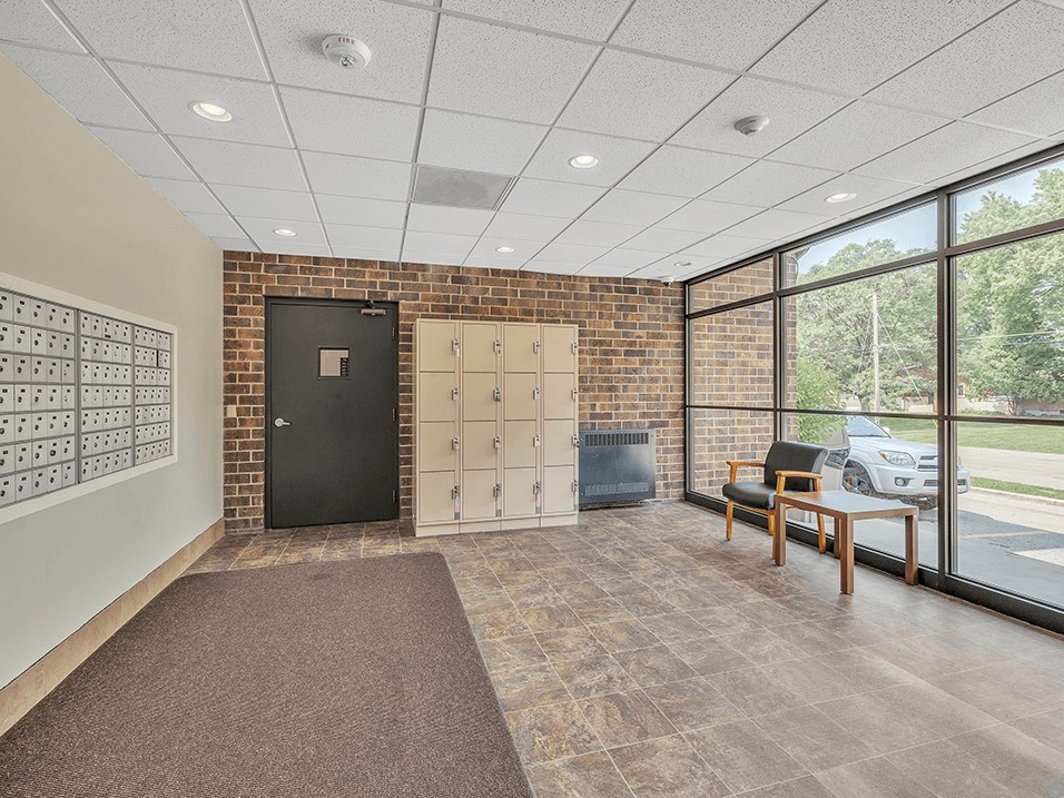 a lockers room with a desk and a chair in a building with large windows