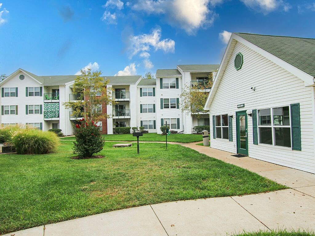 a sidewalk in front of an apartment building with green grass