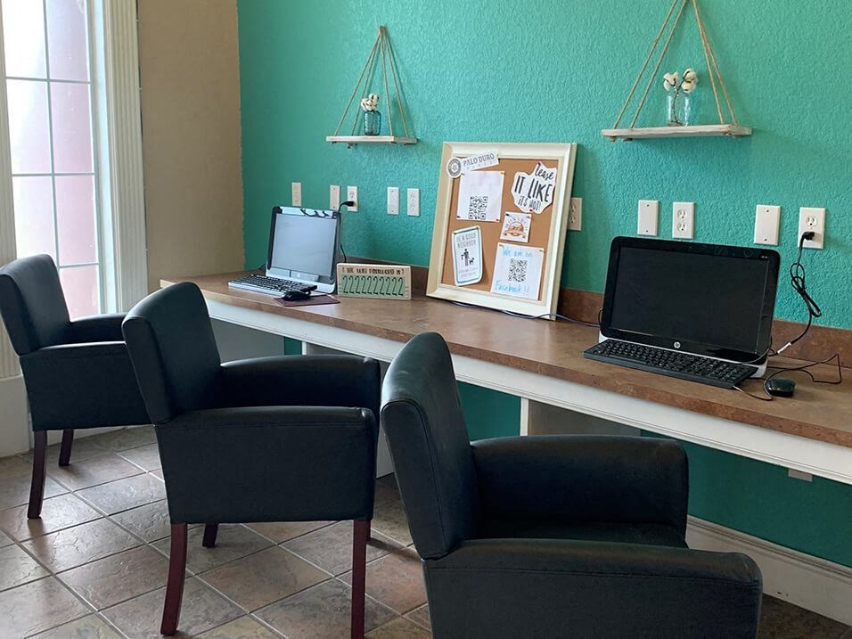a desk with two laptops and three chairs