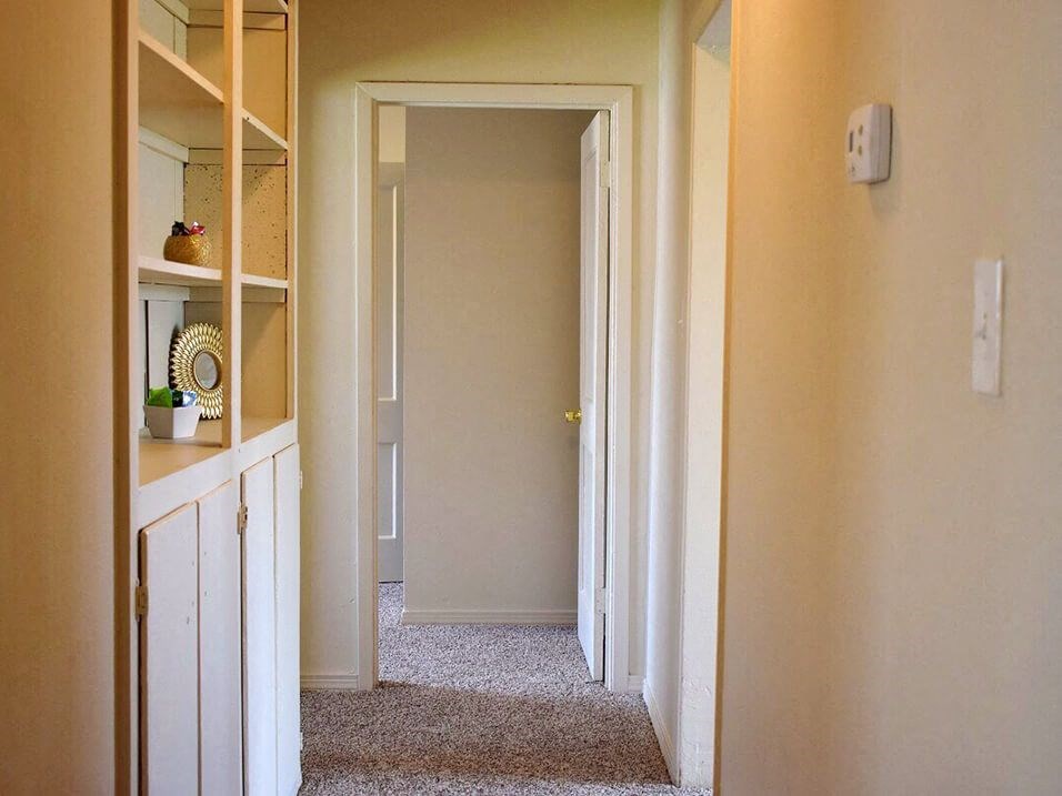 a hallway with yellow walls and a white cabinet
