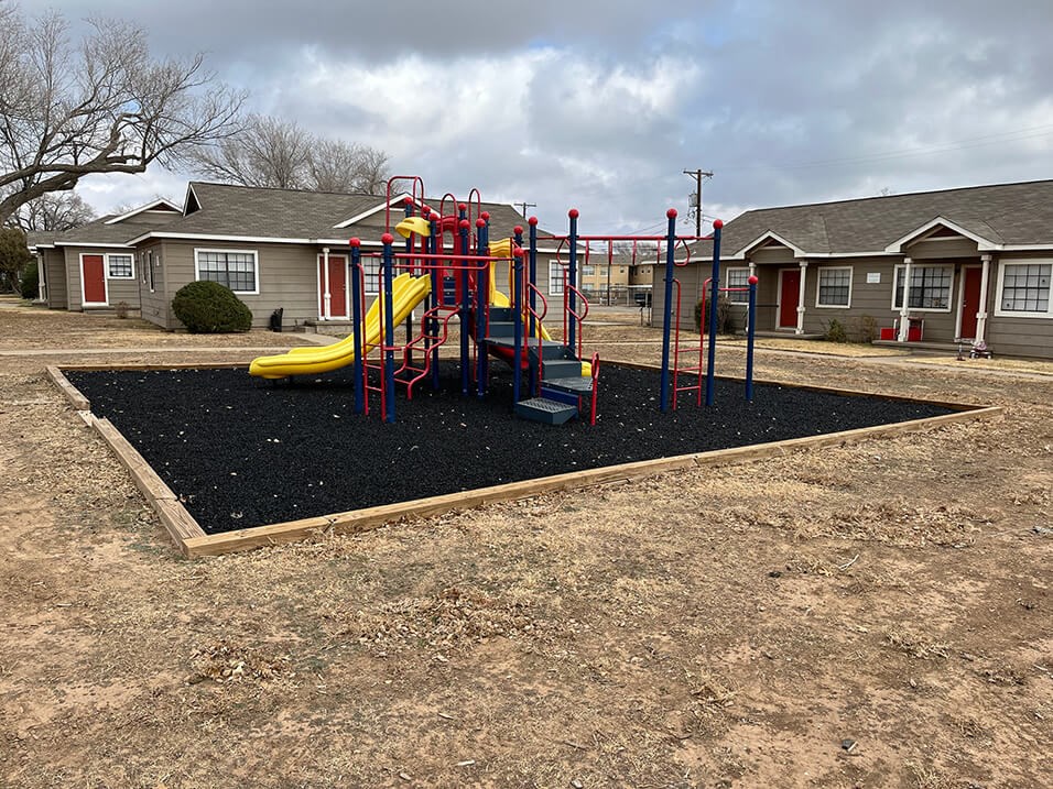 a playground with a slide in front of a row of houses